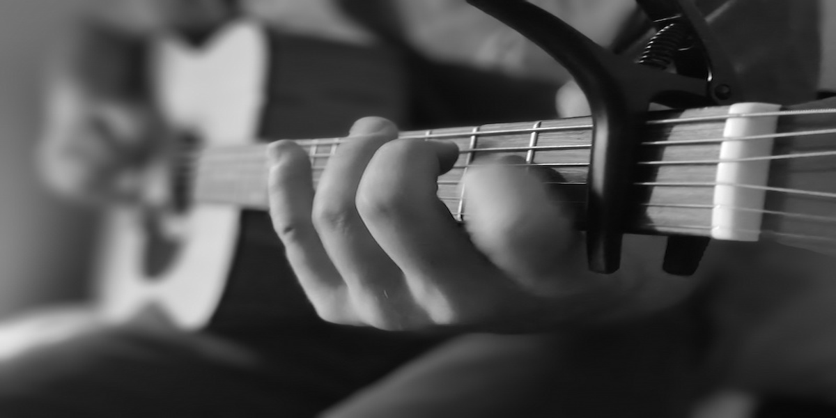 Guitarist playing acoustic guitar. Black and white photo of fingers on acoustic guitar strings